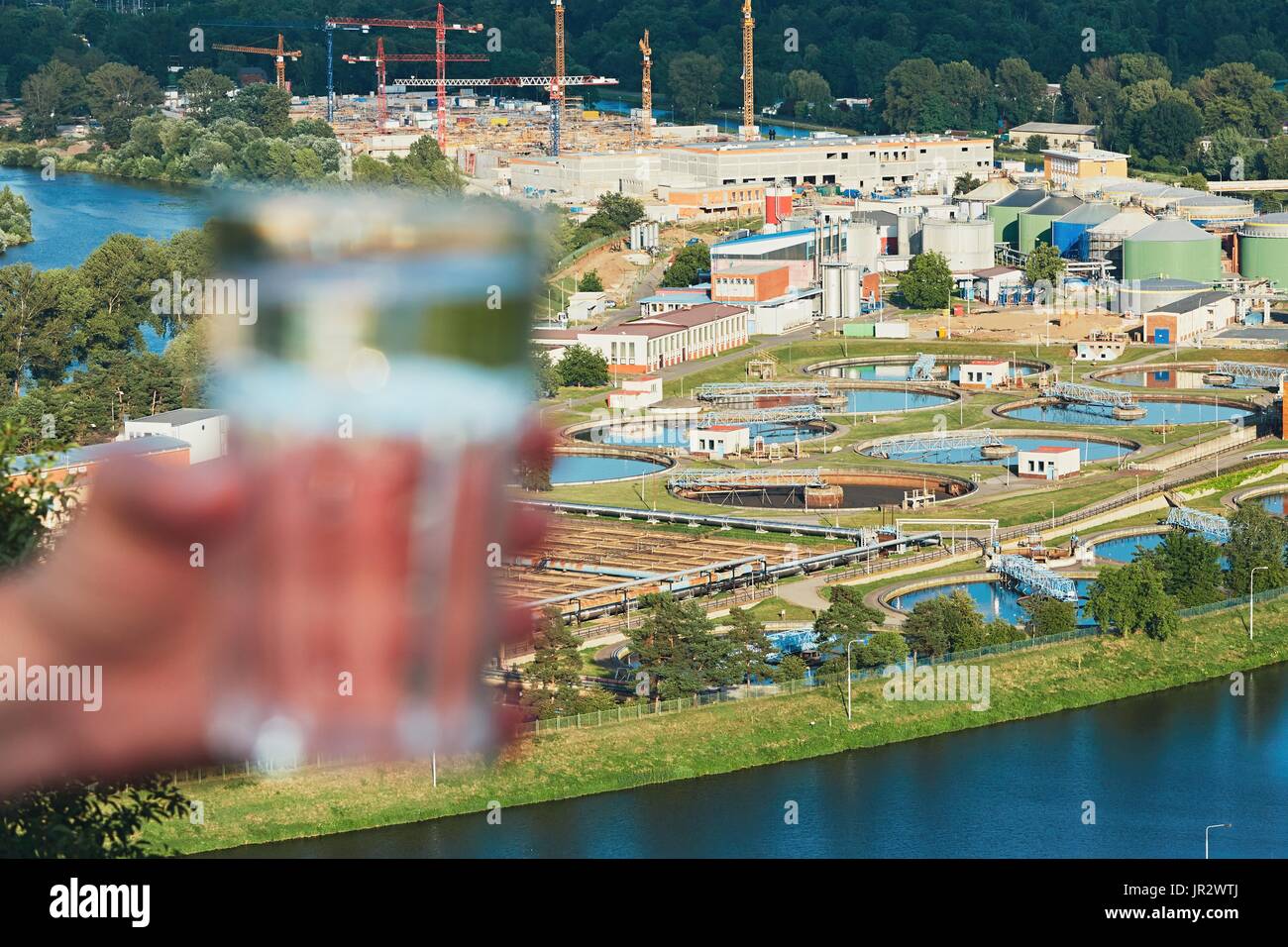 Glass of drinking water and sewage treatment plant - selective focus Stock Photo