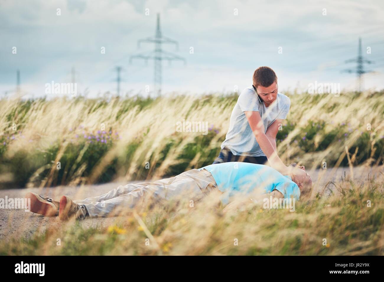 Young man calling for Emergency medical service. Dramatic resuscitation on the rural road. Themes rescue, help and hope. Stock Photo