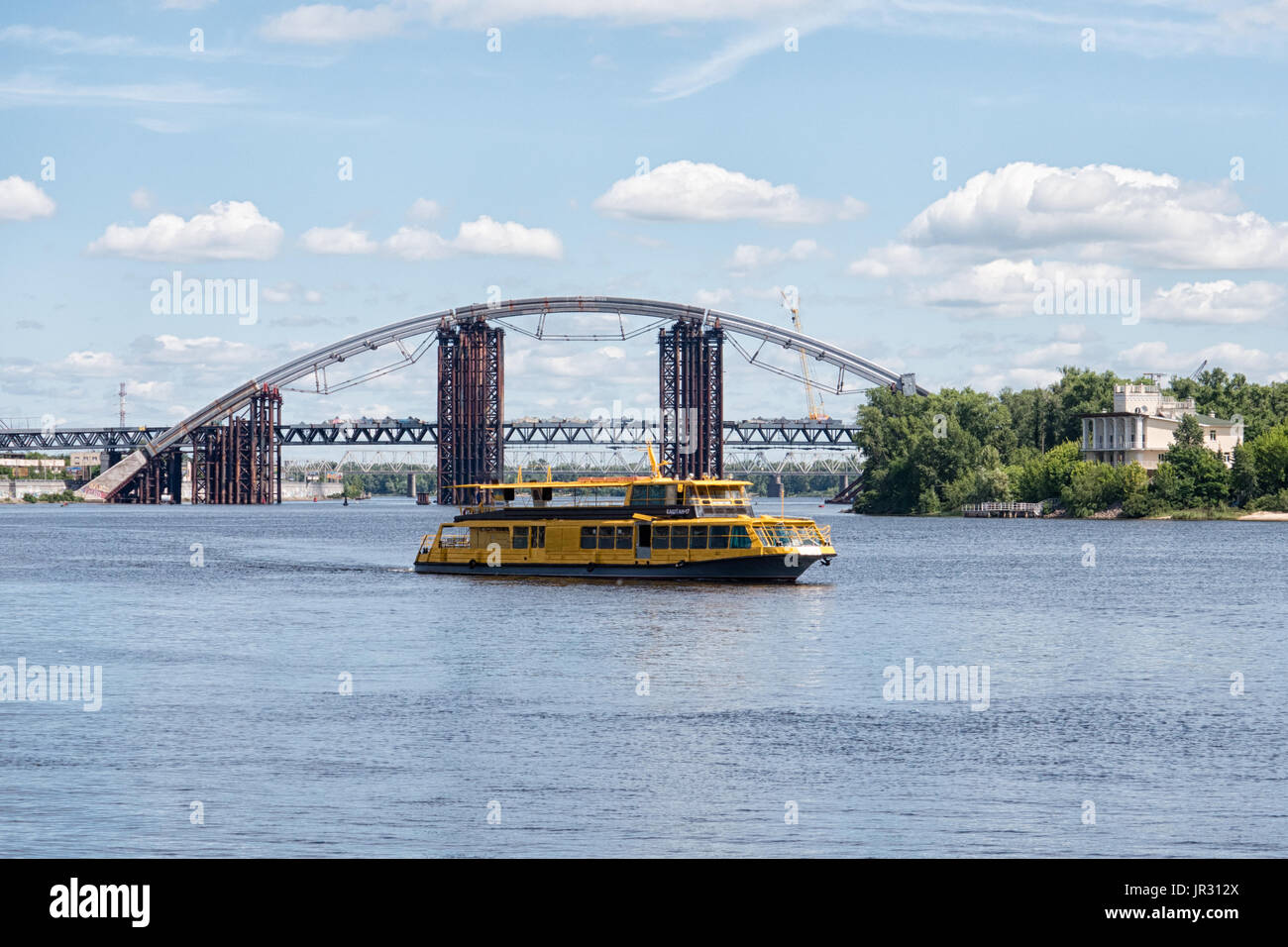 KYIV, UKRAINE - JUNE 12, 2016:  ourist Excursion boat on the Dnieper (Dnipro) River with the Podilsko-Voskresensky Bridge in the background Stock Photo