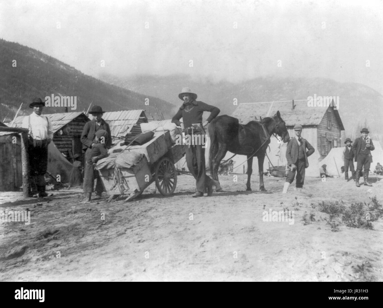 Klondike wagon loaded with provisions. The Klondike Gold Rush was a migration by an estimated 100,000 prospectors to the Klondike region of the Yukon between 1896-99. Gold was discovered by local miners on August 16, 1896 and, when news reached Seattle and San Francisco, it triggered a stampede of would-be prospectors. To reach the gold fields most took the route through the ports of Dyea and Skagway in Alaska. Here, the Klondikers could follow either the Chilkoot or the White Pass trails to the Yukon River and sail down to the Klondike. Each of them was required to bring a year's supply of fo Stock Photo