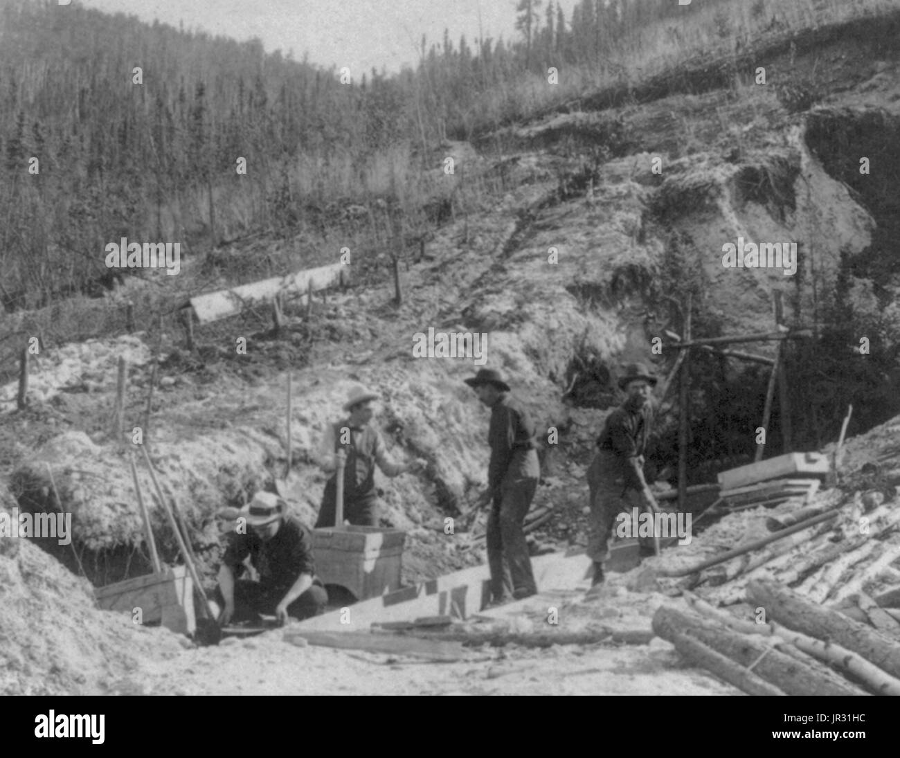 Placer mining for gold at Discovery Claim in the Klondike. The Klondike Gold Rush was a migration by an estimated 100,000 prospectors to the Klondike region of the Yukon between 1896-99. Gold was discovered by local miners on August 16, 1896 and, when news reached Seattle and San Francisco, it triggered a stampede of would-be prospectors. To reach the gold fields most took the route through the ports of Dyea and Skagway in Alaska. Here, the Klondikers could follow either the Chilkoot or the White Pass trails to the Yukon River and sail down to the Klondike. Each of them was required to bring a Stock Photo