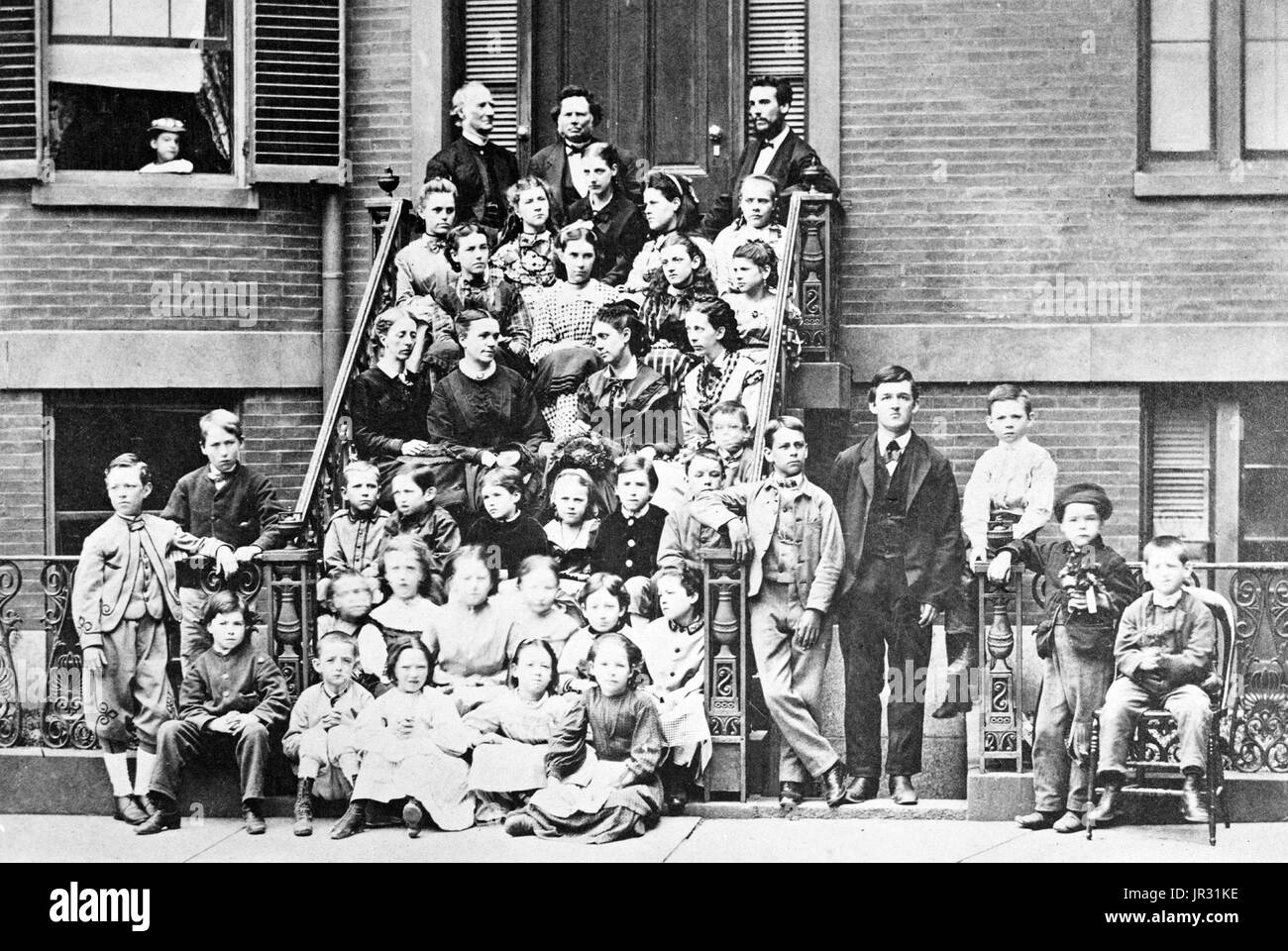 Bell, on top step with Dexter King, founder of the school, and Ira Allen, chairman of school committee, three steps down are teachers Annie Bond, Sarah Fuller, Ellen Barton, and Mary True, students are seated on the steps and standing on the sidewalk at entrance to the Pemberton Square School (Boston School for the Deaf). Alexander Graham Bell (March 3, 1847 - August 2, 1922) was a Scottish-American speech therapist and inventor of the telephone. Bell followed his father and grandfather into the speech therapy profession, but also studied sound waves and the mechanics of speech. By 1871, he ha Stock Photo