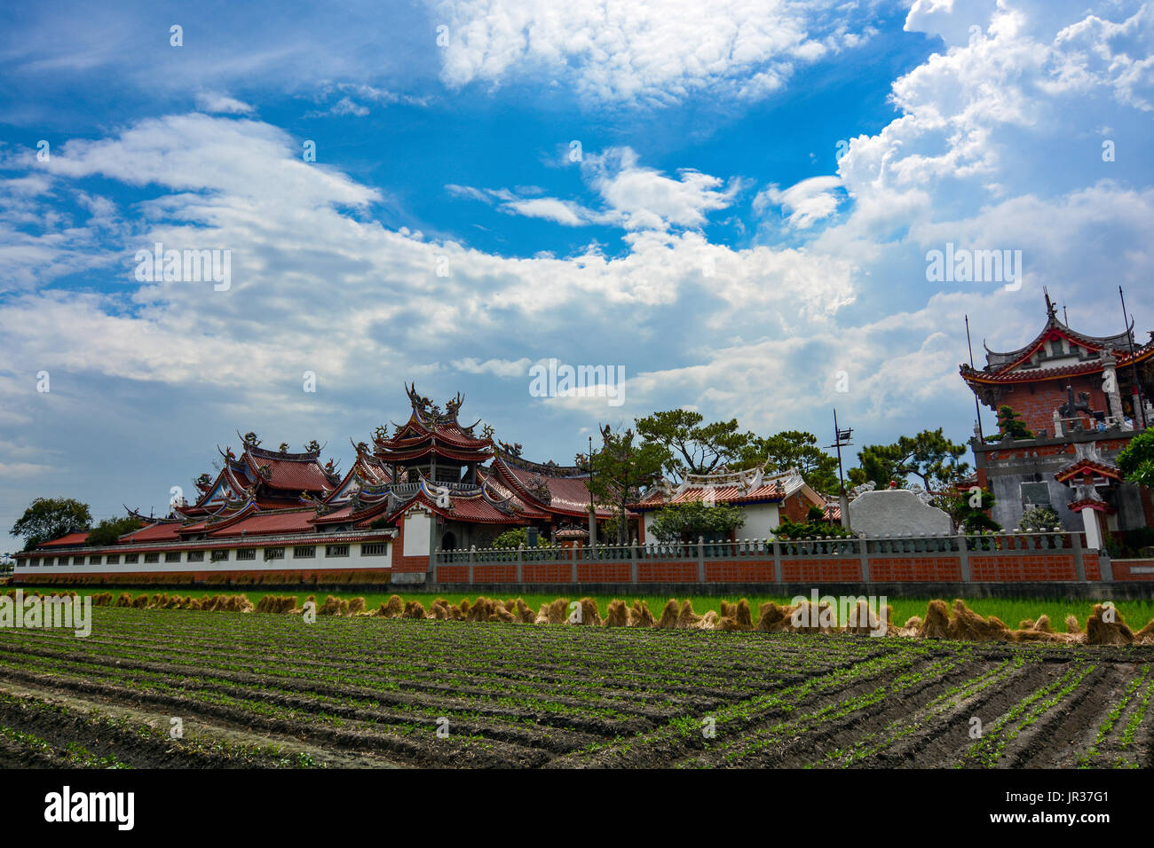 Newly planted farmland and Chinese style rooftops of the old Huwei Chifa Matsu Temple in Yunlin County, Taiwan Stock Photo