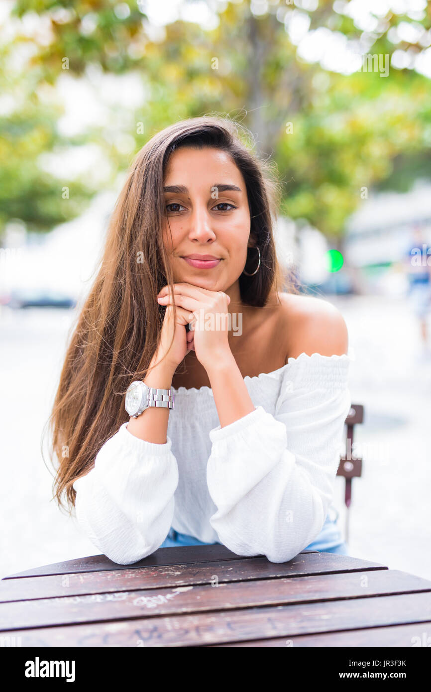 Young beautiful woman sitting outdoors in the park at bench Stock Photo ...