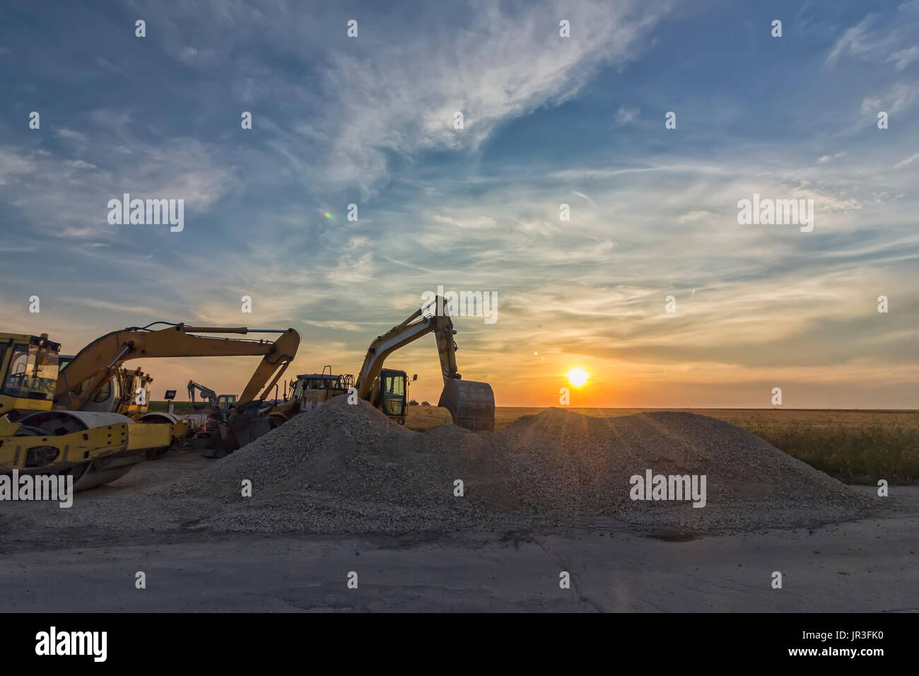 excavators in construction site at stunning sunset Stock Photo - Alamy