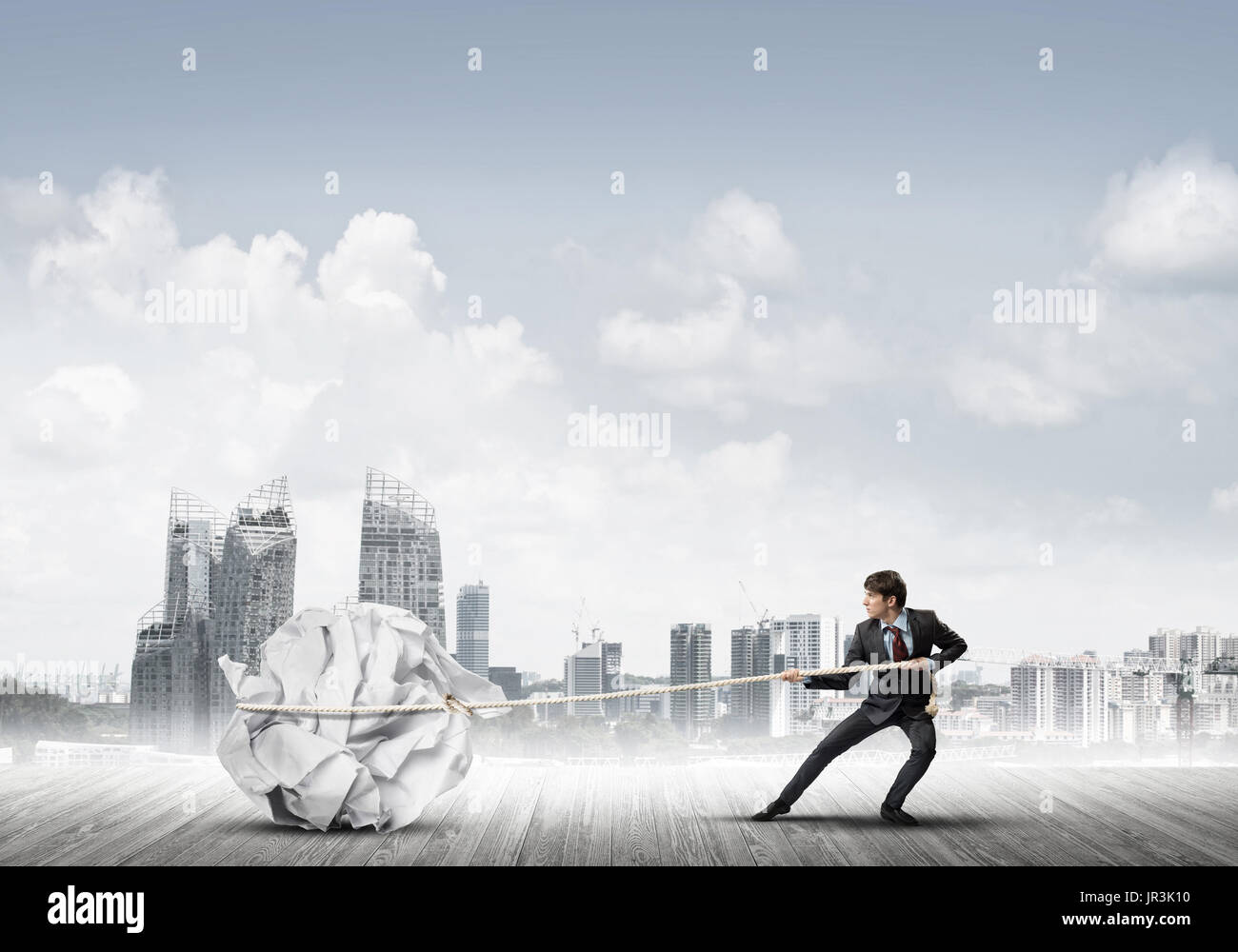 Man pulling with effort big crumpled ball of paper as creativity sign