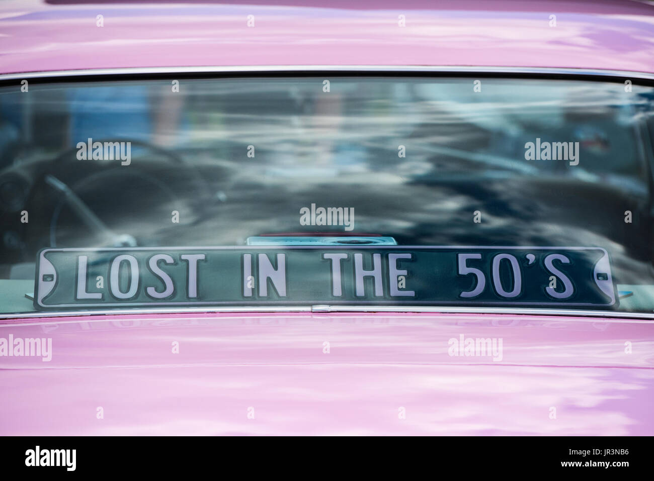 1959 Pink Cadillac rear window with Lost in the 50s sign at an american car show. UK Stock Photo
