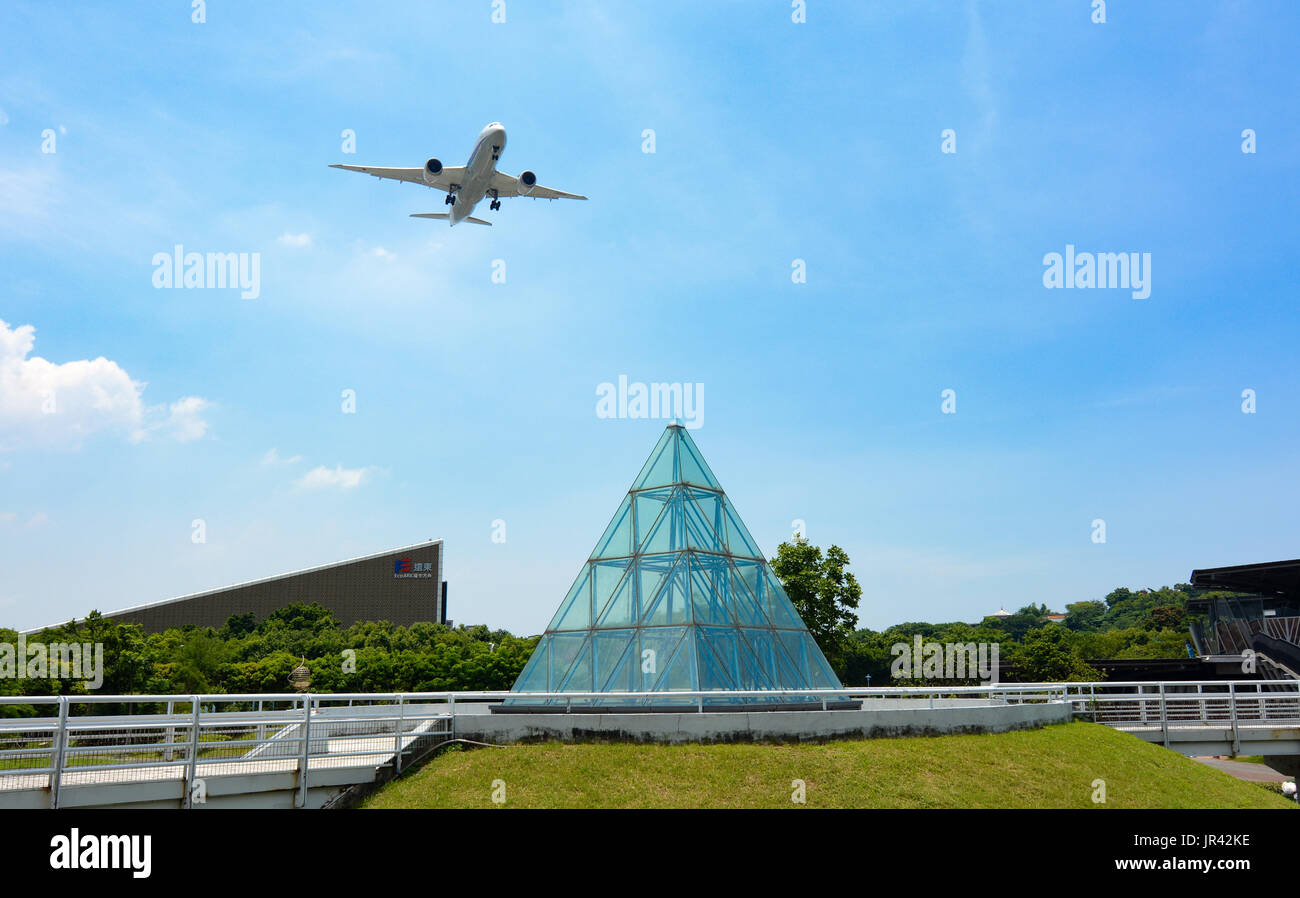 TAIPEI, TAIWAN - JULY 1, 2017 - Commercial passenger plane deploying landing gear over Taipei Expo Park to land at Songshan Airport Stock Photo