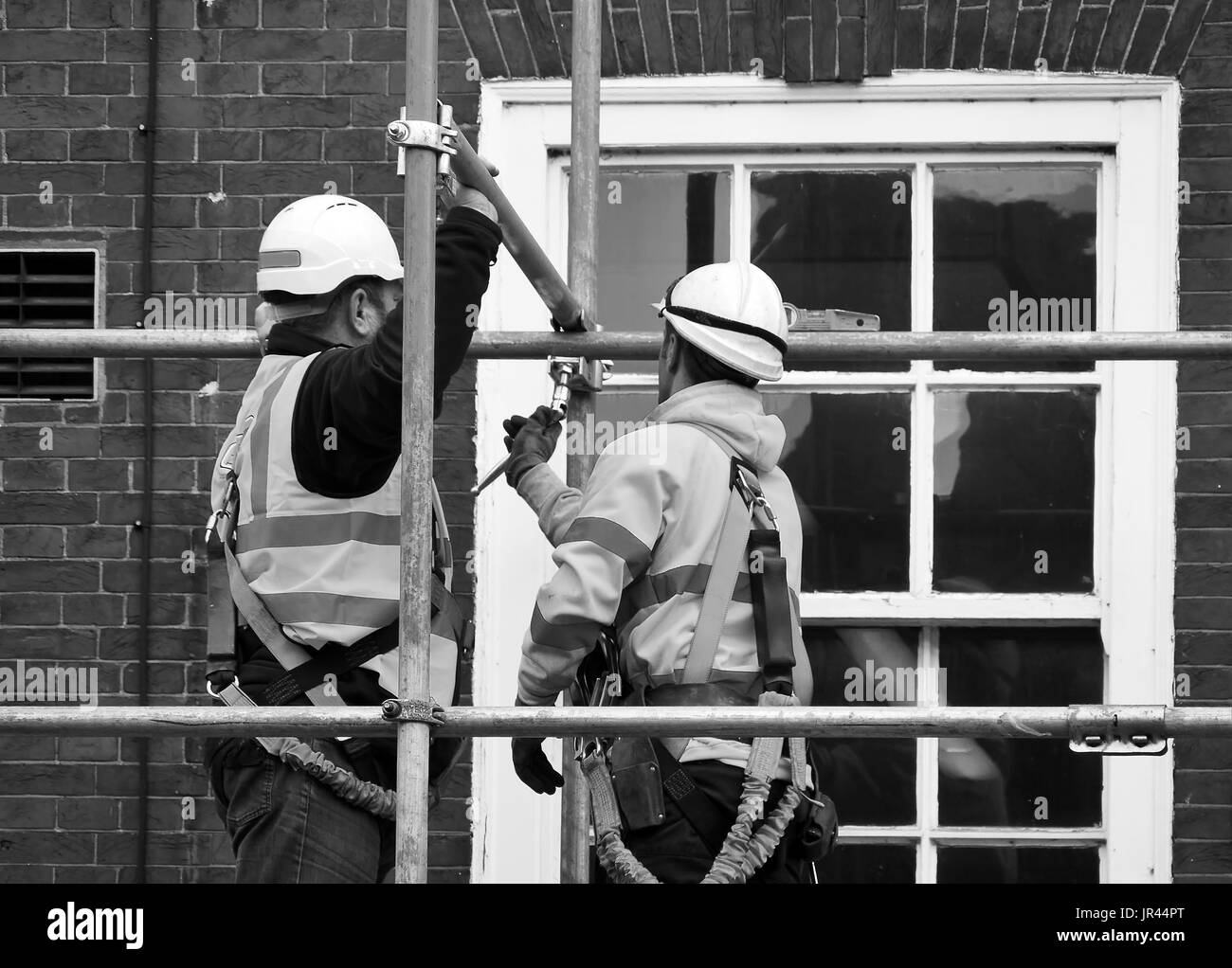 Two workers assembling scaffolding on city building Stock Photo