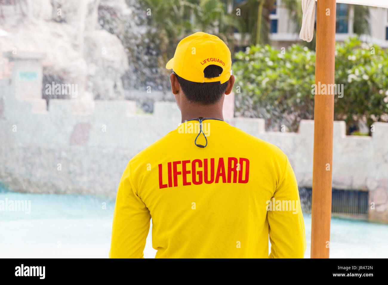 back side of lifeguard man wearing yellow lifeguard shirt and cap