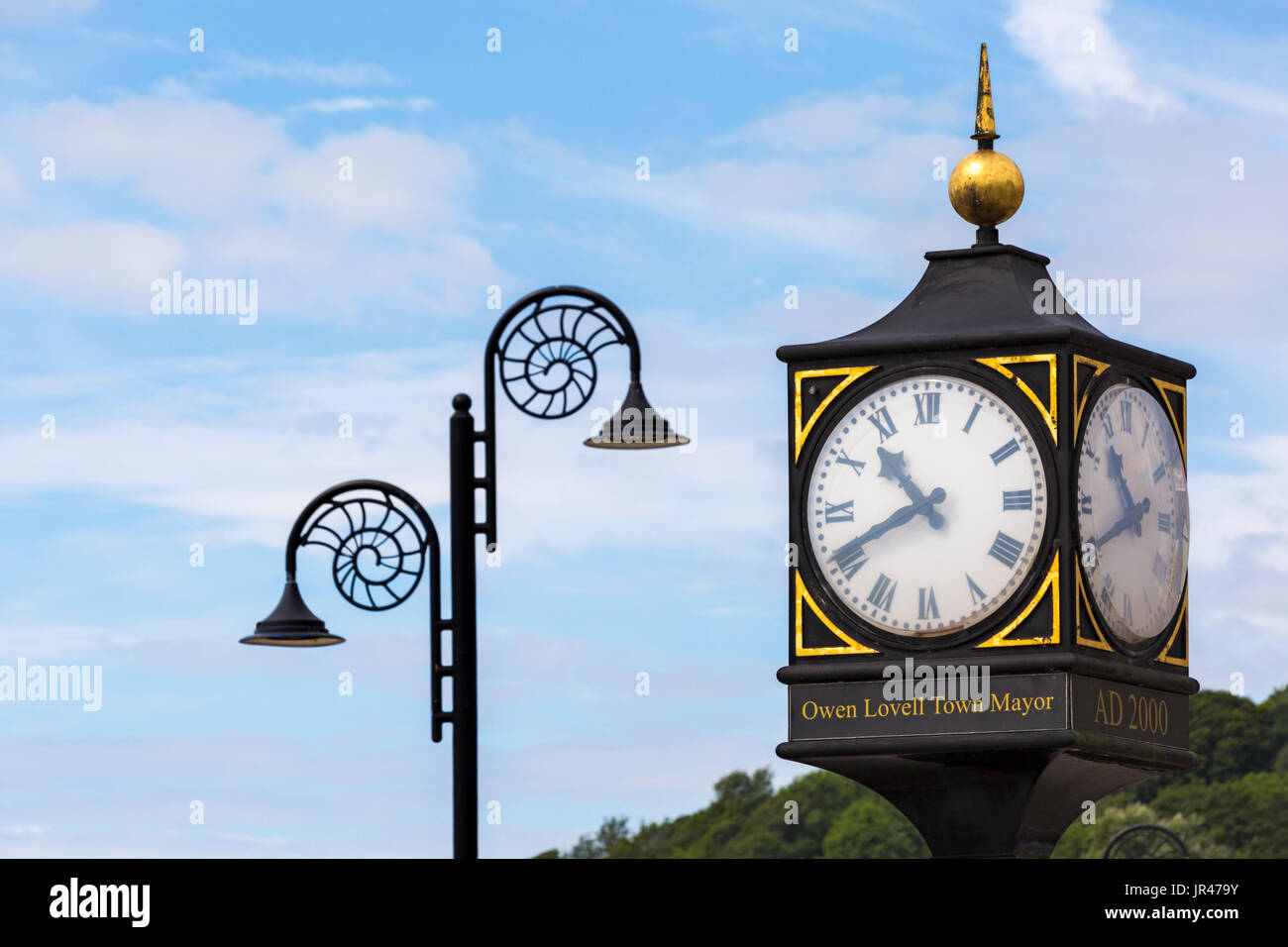 Millennium Clock at Cobb Gate with ornate Ammonite design streetlamps at Lyme Regis, Dorset in July Stock Photo