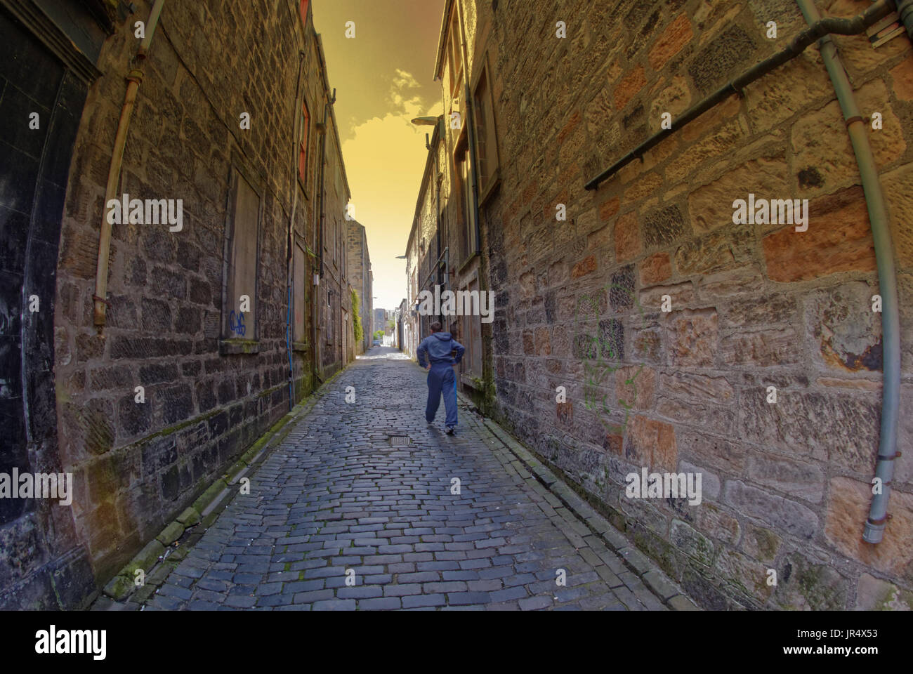 young boy running down alley way in perspective Stock Photo