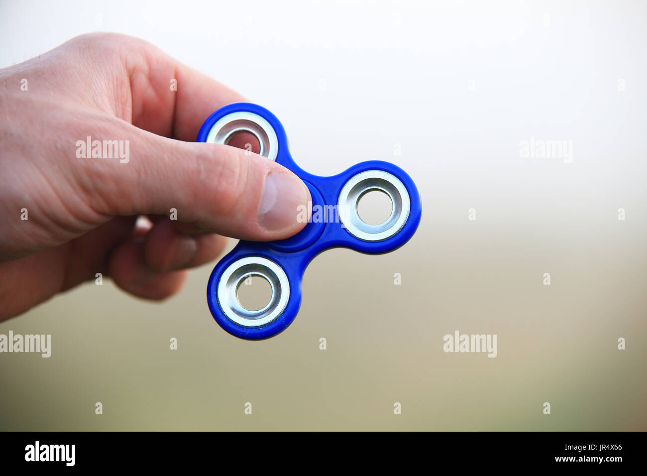 Spinner in hand close-up. Hand holds blue fidget closeup. Stock Photo
