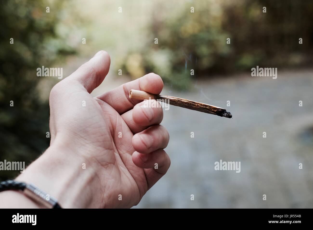 White man holding joint in his hand. Marijuana smoking concept. Stock Photo