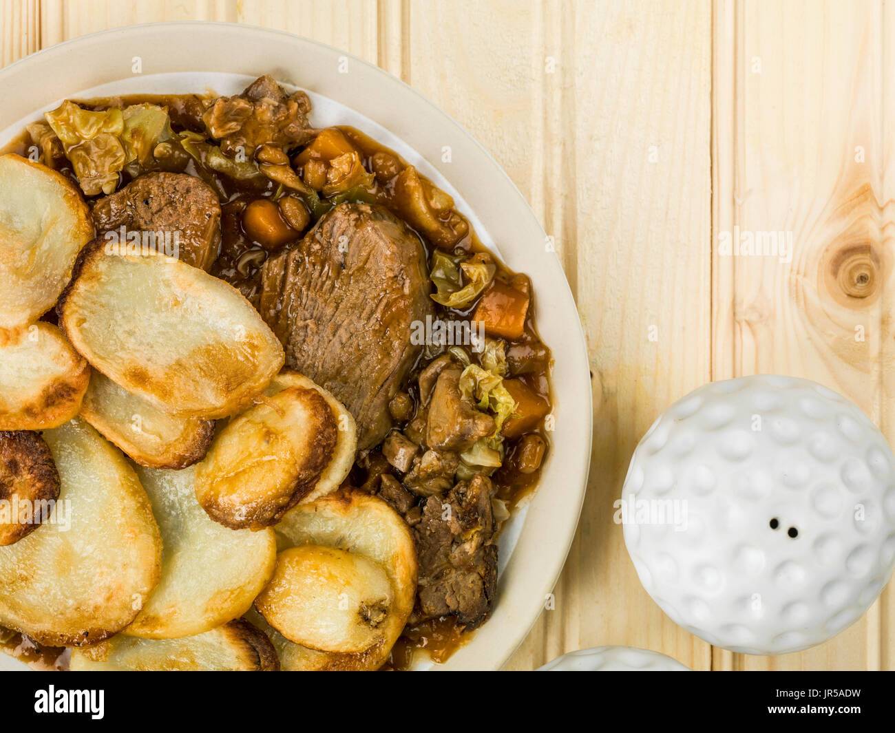 Lamb Hotpot With Sliced Potatoes and Onion Gravy Against a Light Pine Wood Wooden Background Stock Photo