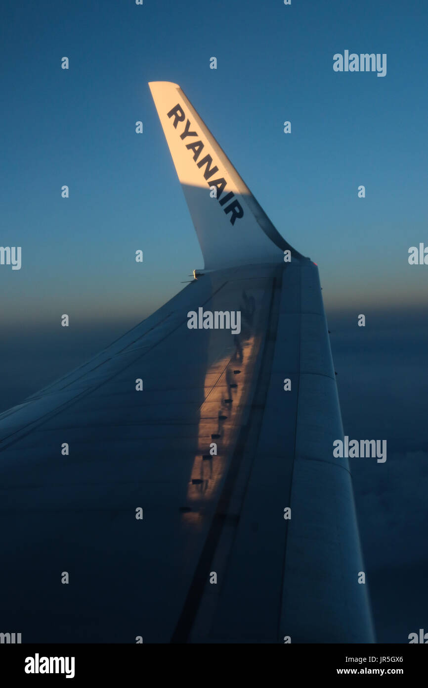 The Winglet of a Ryanair Boeing 737-800 glistens in the setting sun as the light is reflected in the sky behind Stock Photo