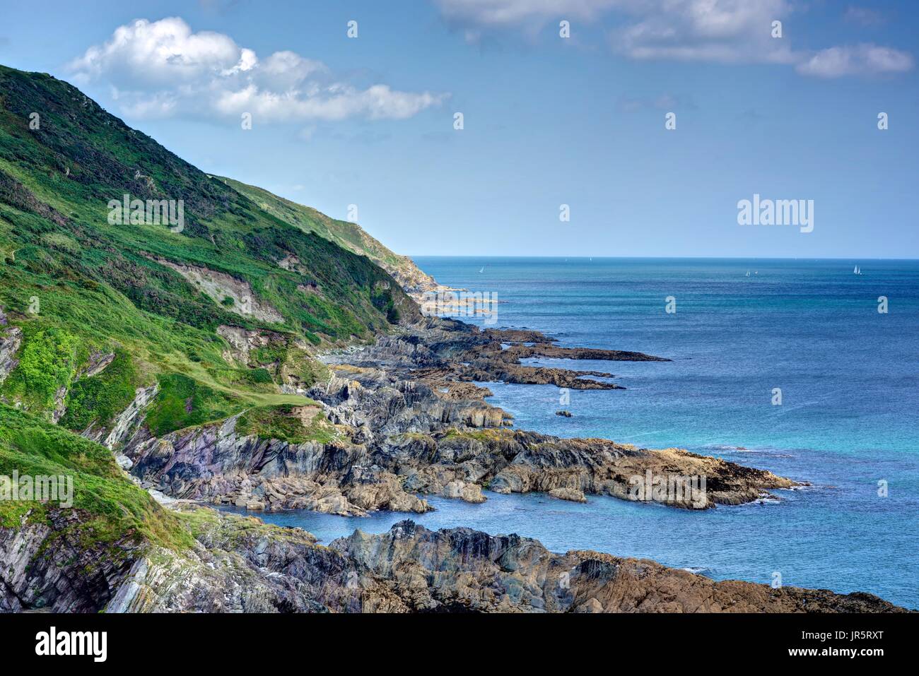 A beautiful picturesque landscape of Cornish coastline with azure blue sea taken from a stretch of the South West Coast Path looking towards Polperro. Stock Photo
