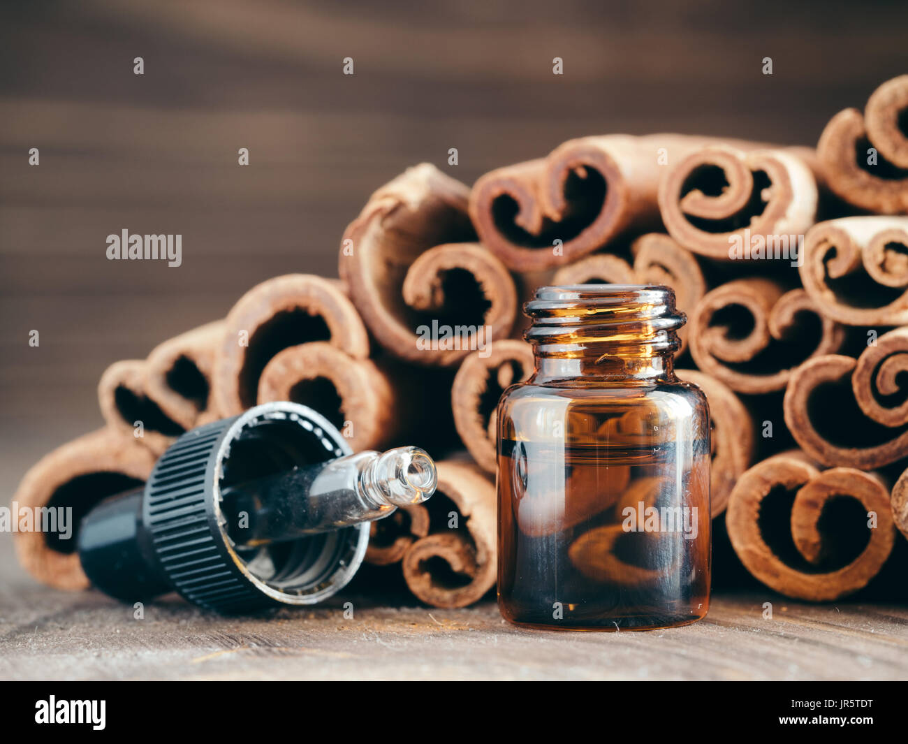 Essential cinnamon oil in brown glass small bottle with pipette on cinnamob sticks background. Copy space. Stock Photo