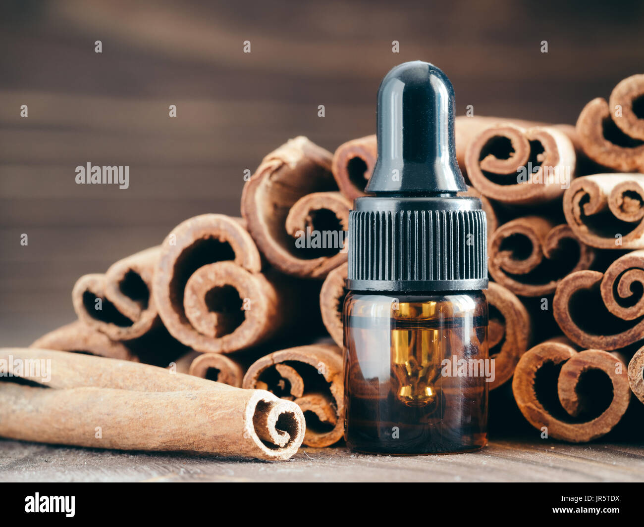 Essential cinnamon oil in brown glass small bottle with pipette on cinnamob sticks background. Copy space. Stock Photo