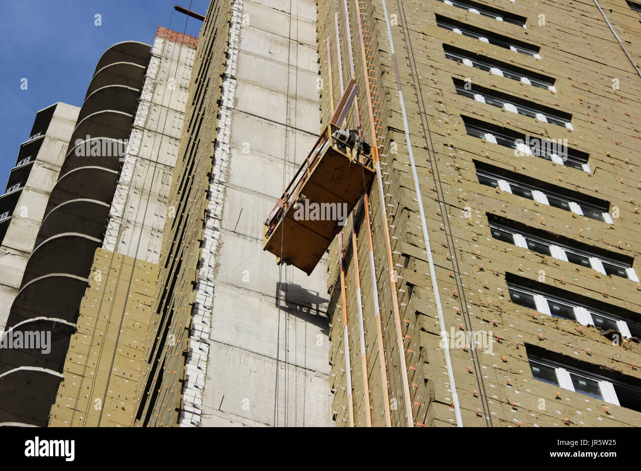 worker in yellow suspended cradle mounts environmental boards for