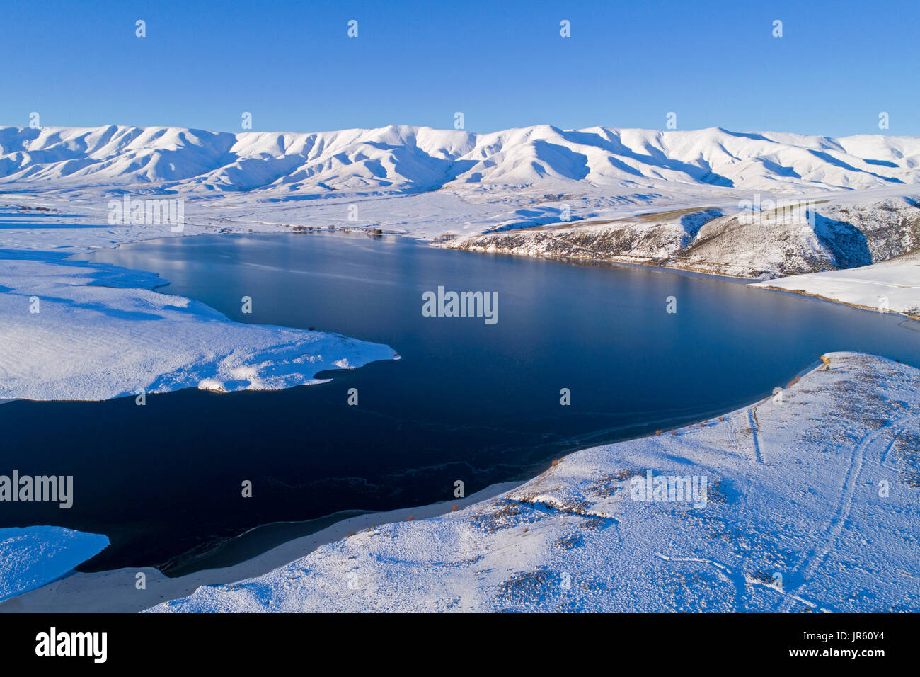 Falls Dam and Hawkdun Range in winter, Maniototo, Central Otago, South Island, New Zealand - drone aerial Stock Photo