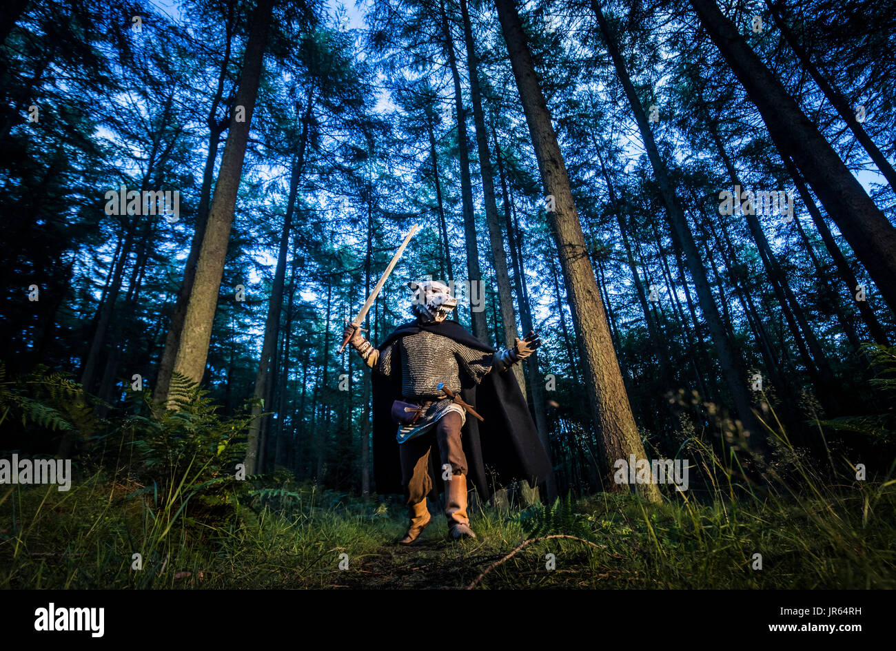 NOTE: A tungsten white balance has been used in daily light conditions along with orange flash gels to create this image. A House of Stark Direwolf mask is modelled near Reasty Hill in the North York Moors National Park ahead of the launch of a series of four official Game of Thrones masks. Stock Photo