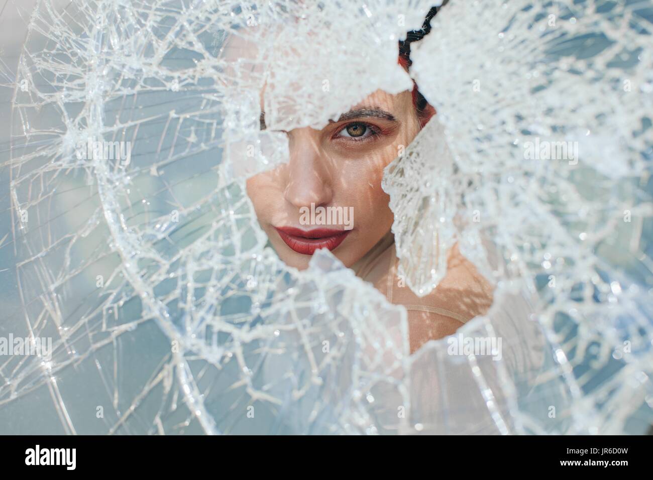 Woman looking through a broken window Stock Photo