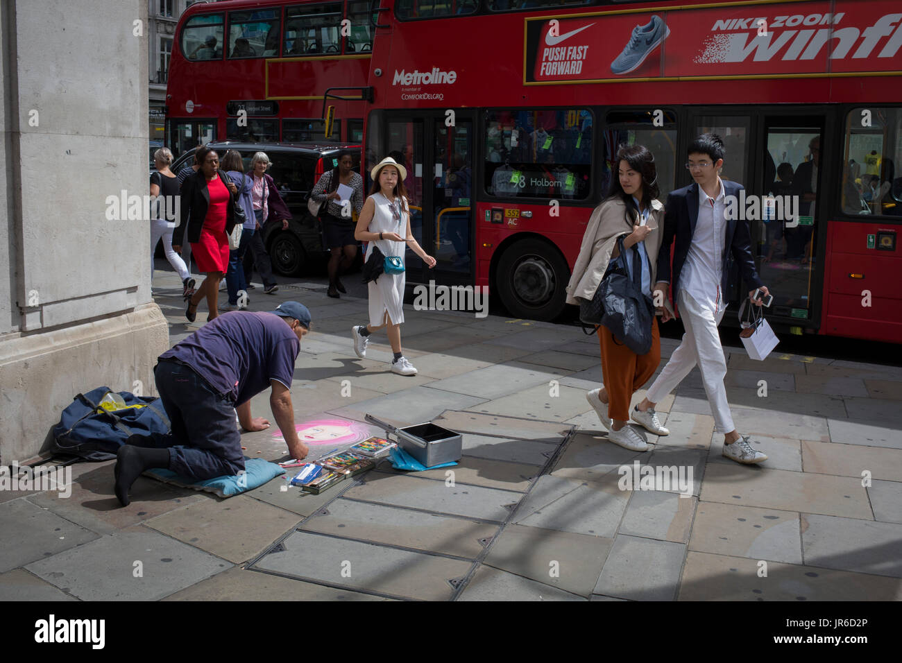 Street artist Nick C makes a pastel portrait of a girl on pink, for shoppers and pedestrians, on 31st July 2017, in Oxford Street, London, England. Stock Photo