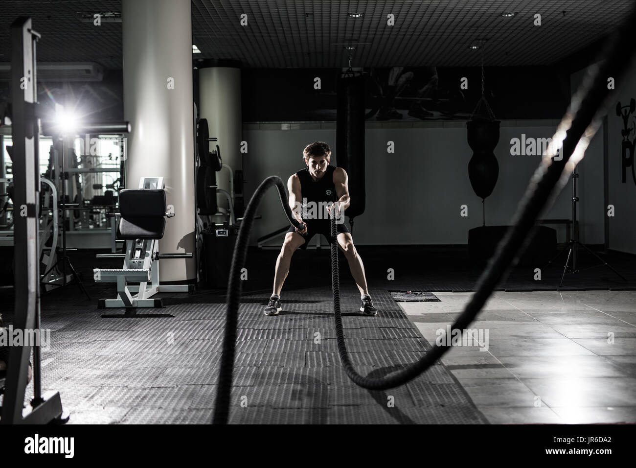 Fitness man working out with battle ropes at gym. Battle ropes