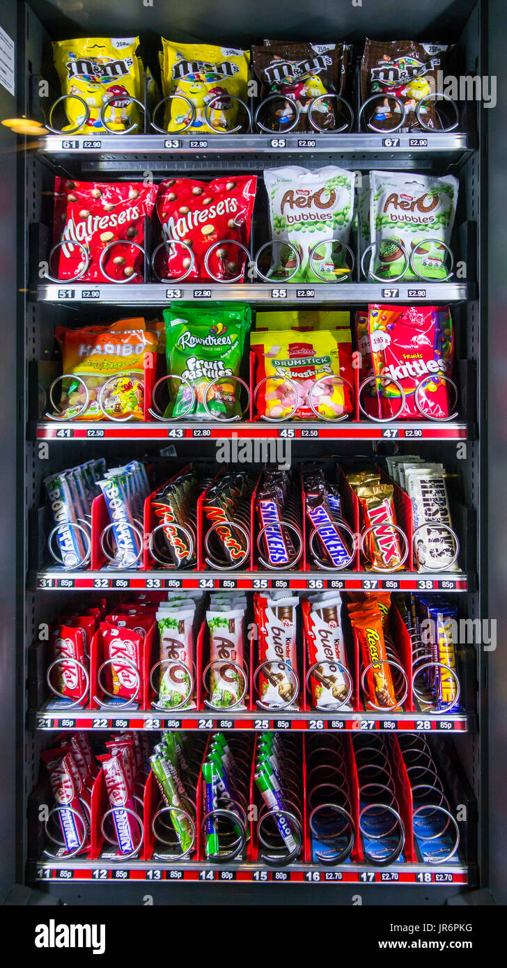 Snack vending machine / snack dispenser selling colourful sweets and chocolate bars in public place Stock Photo