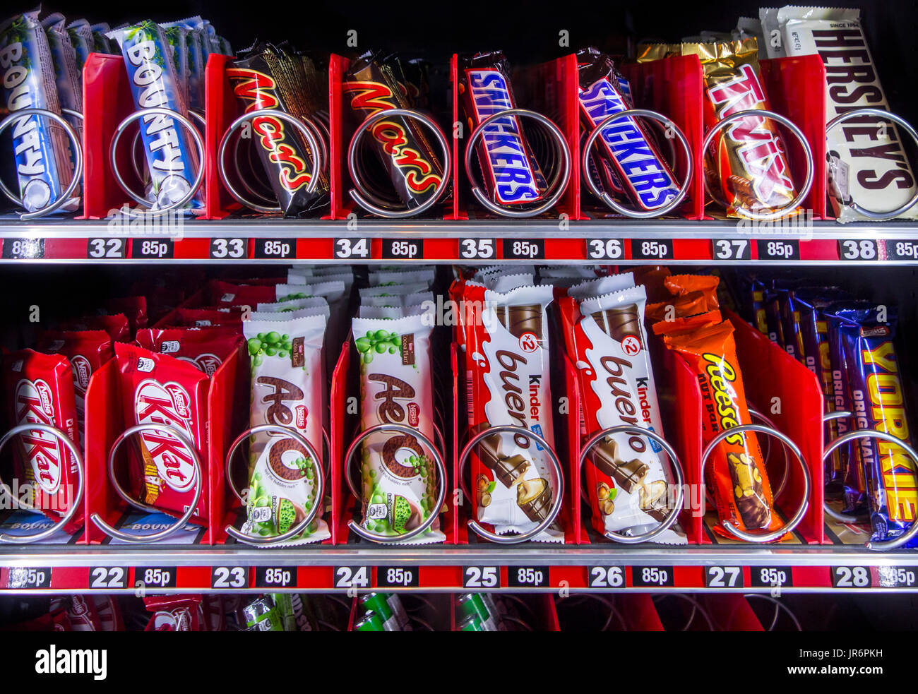 Snack vending machine / snack dispenser selling colourful sweets and chocolate bars in public place Stock Photo
