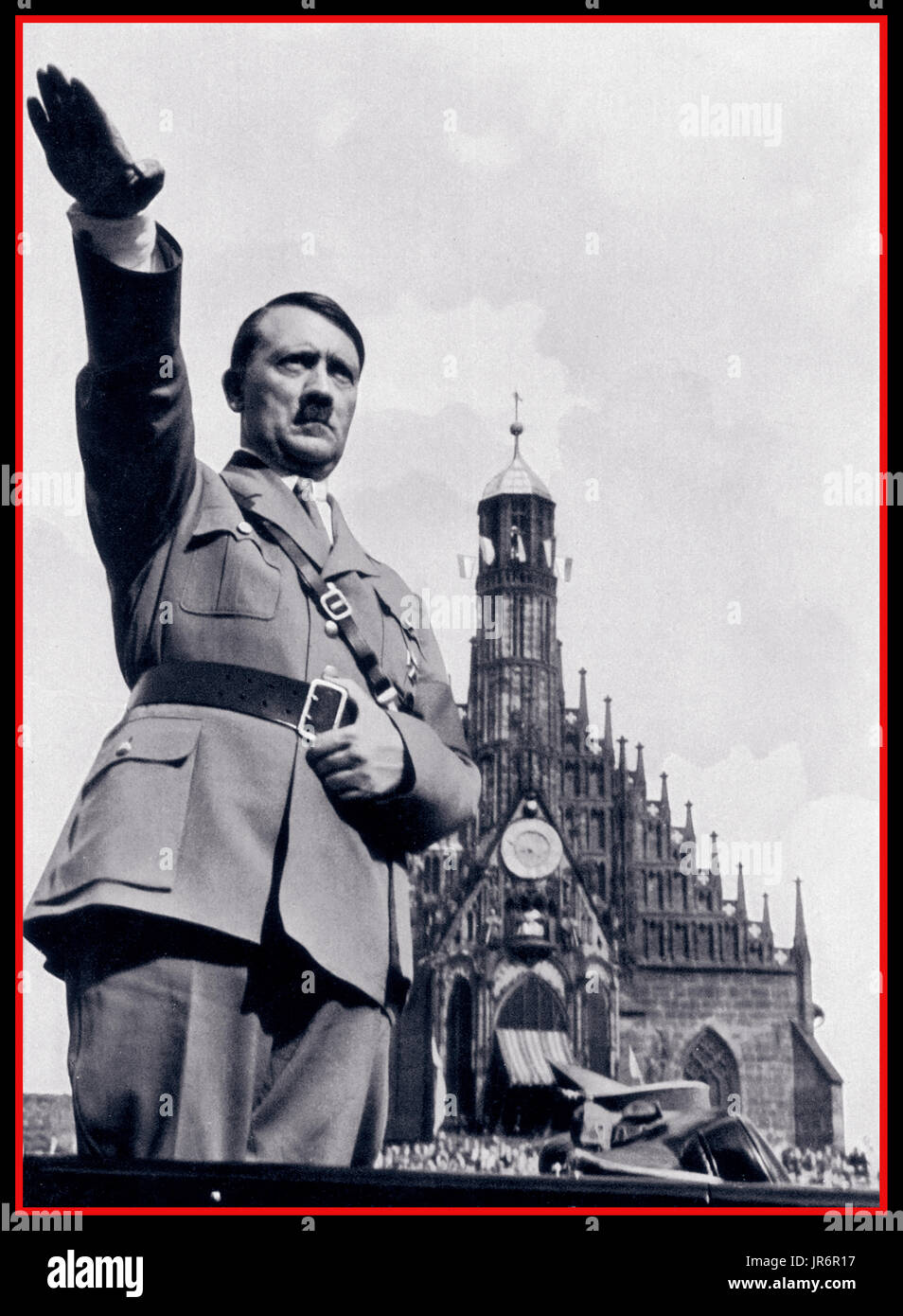 Führer Adolf Hitler in military uniform gives Nazi Heil Hitler salute from his car whilst at a Nazi Party Rally in the 1930's Adolf Hitler salutes  crowd from his open car at Reichsparteitag parade Nuremberg Germany Stock Photo