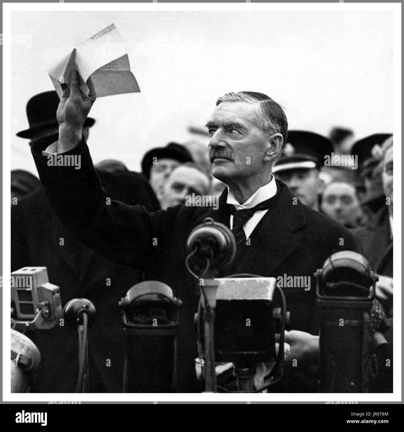 Neville Chamberlain 1938 holds 'the' piece of paper proudly aloft signed by both Hitler and himself on his return from Munich to Heston Aerodrome in 1938 with the quote; 'a desire never to go to war again...!' Stock Photo