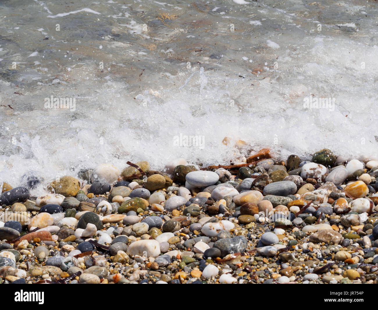 Wet pebbles on a sea shore Stock Photo