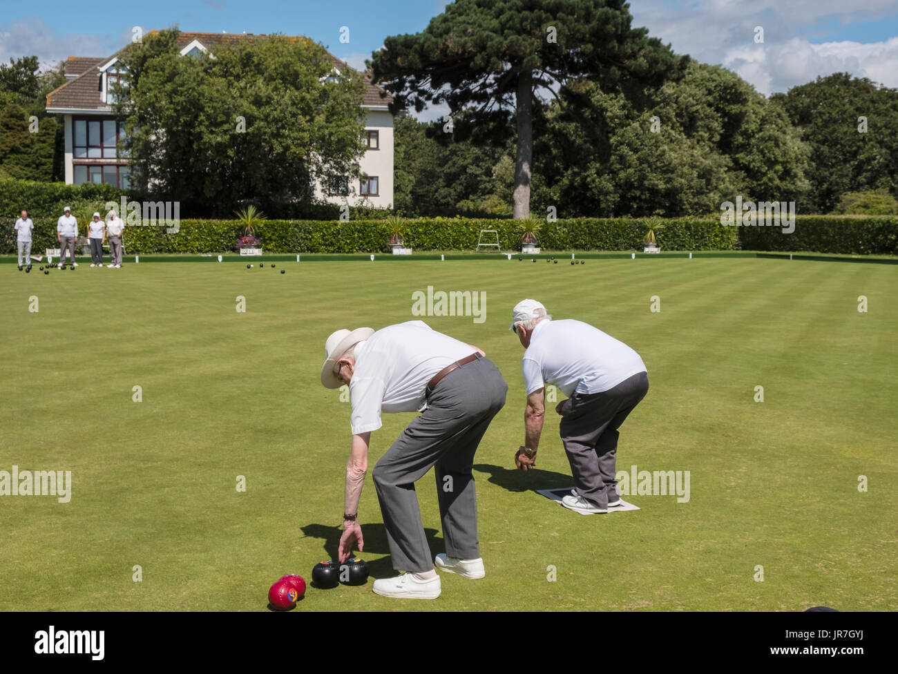 Two men bending down to play bowls on a bowling green at the Argyll Bowling Club, Westbourne, Bournemouth, Dorset, UK Stock Photo
