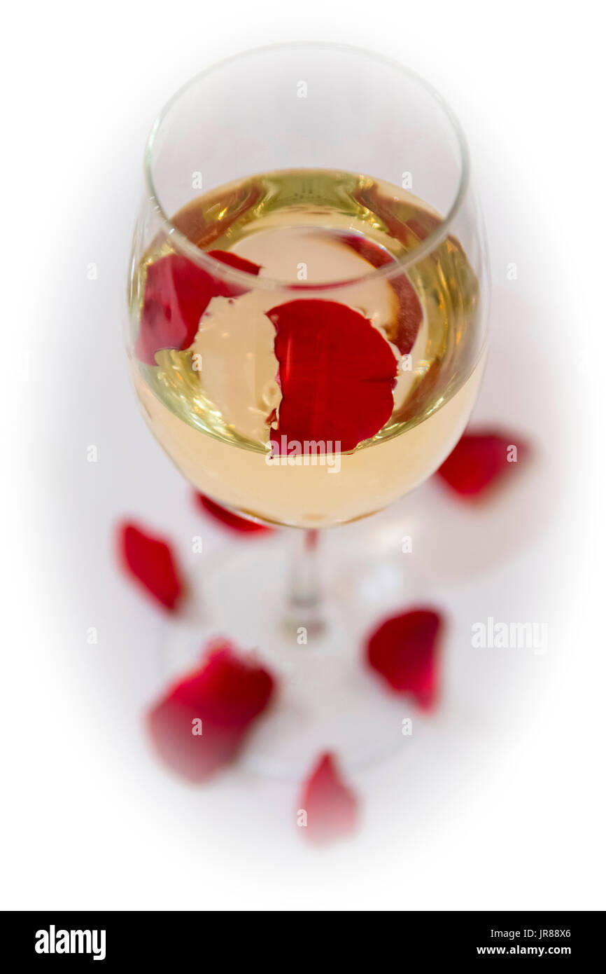 Glass with white wine and some red rose petals Stock Photo - Alamy
