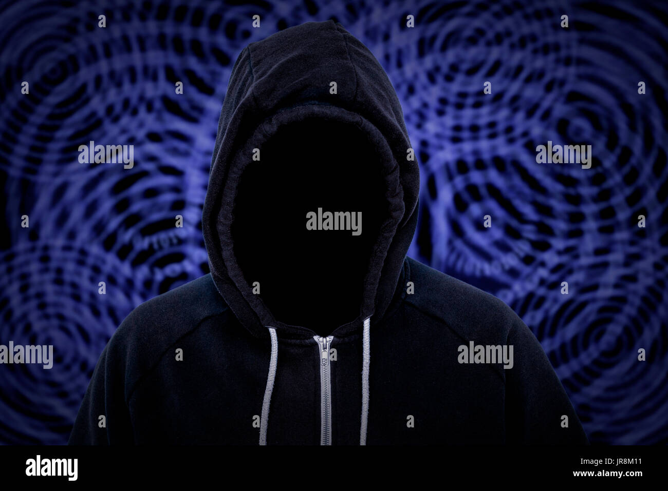 Unknown faceless hooded cyber criminal with binary code in the background Stock Photo