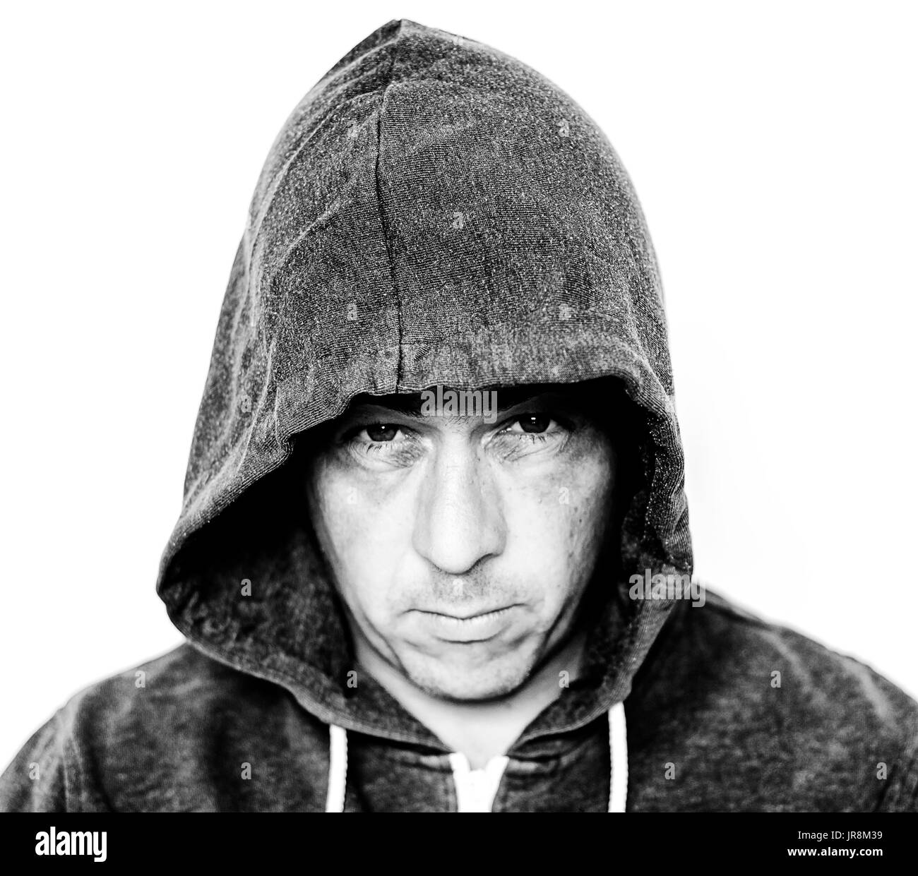 Man wearing a grey hooded top showing a mean grungy face with added grunge effect in black and white Stock Photo