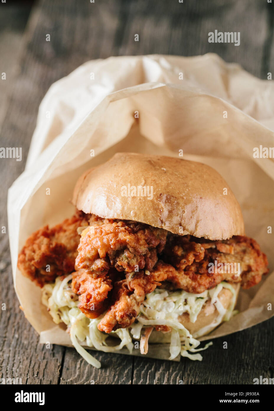Fried boneless chicken sandwich with coleslaw on wooden surface Stock Photo