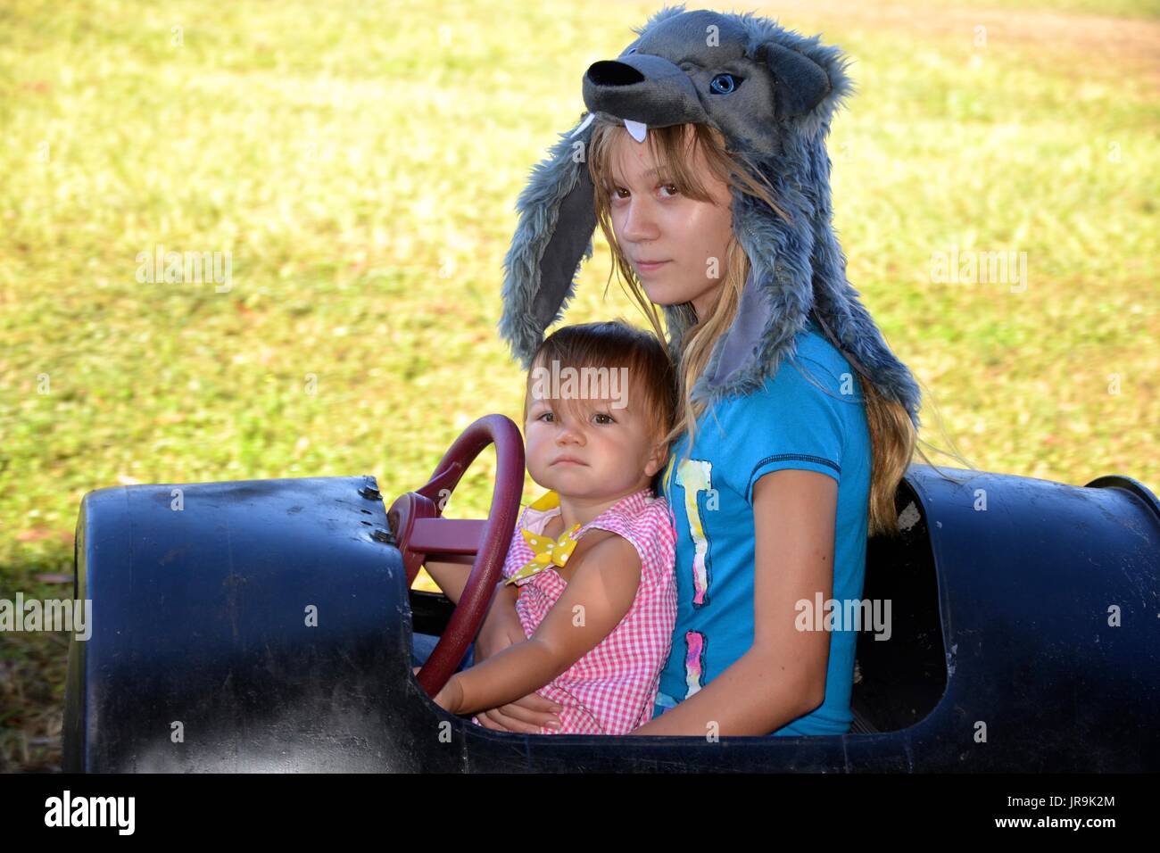 Young girl and female toddler (sisters) riding a barrel train at a fall festival. Stock Photo