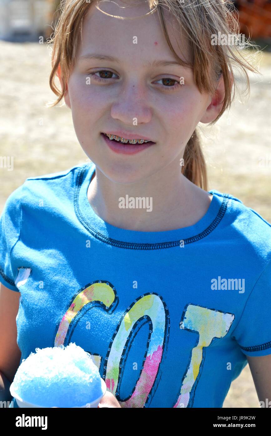 Young girl enjoying a festival and having an snow cone at a festival. Stock Photo