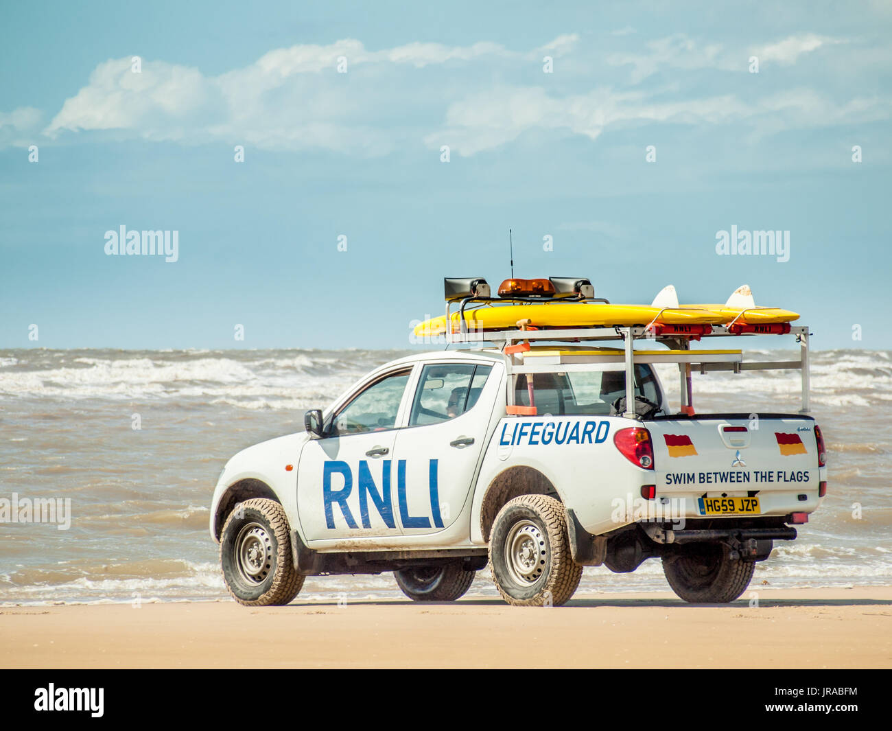 RNLI Pickup Truck on a beach with a surfboard Stock Photo