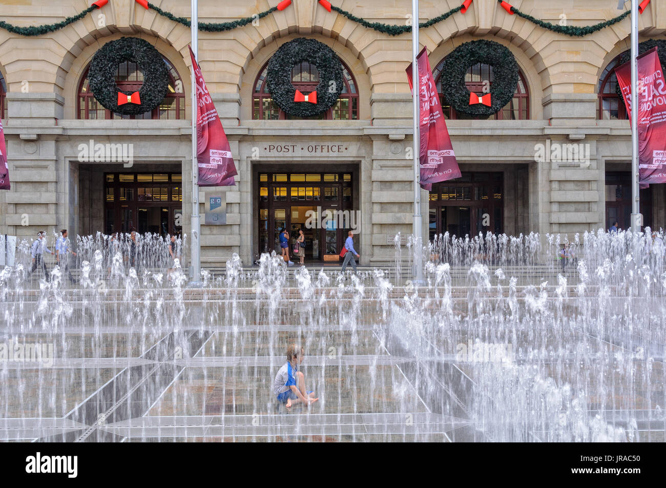 A boy enjoys a fountain refreshment in the summer heat in front of the old General Post Office in Forrest Place - Perth, WA, Australia Stock Photo