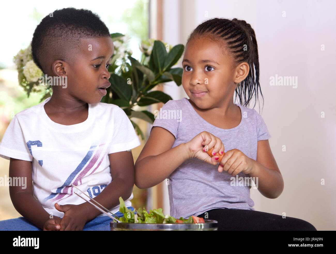 Little girl breaking a carrot to share with her brother Stock Photo