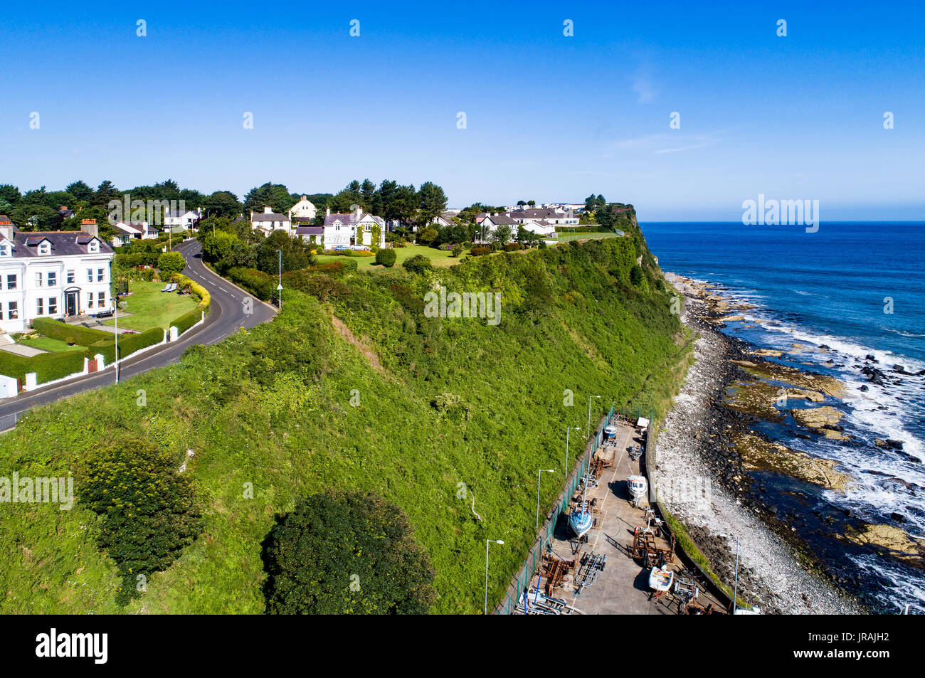Atlantic coast with a steep cliff, marina and Causeway Coastal Road at Ballycastle, County Antrim, Northern Ireland, UK. Aerial view Stock Photo