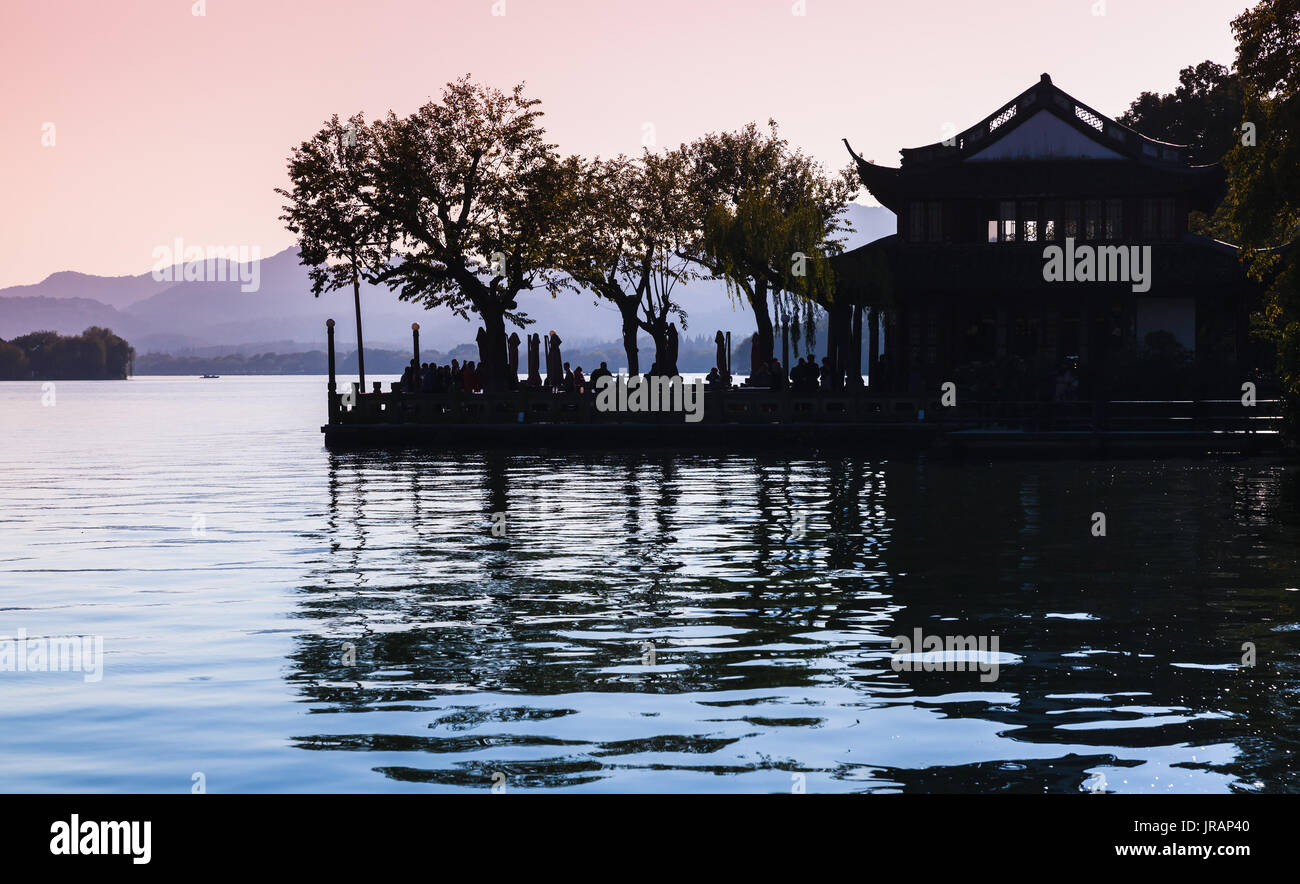 Black trees silhouette and traditional Chinese buildings on the coast of West Lake. Famous public park in Hangzhou city, China Stock Photo