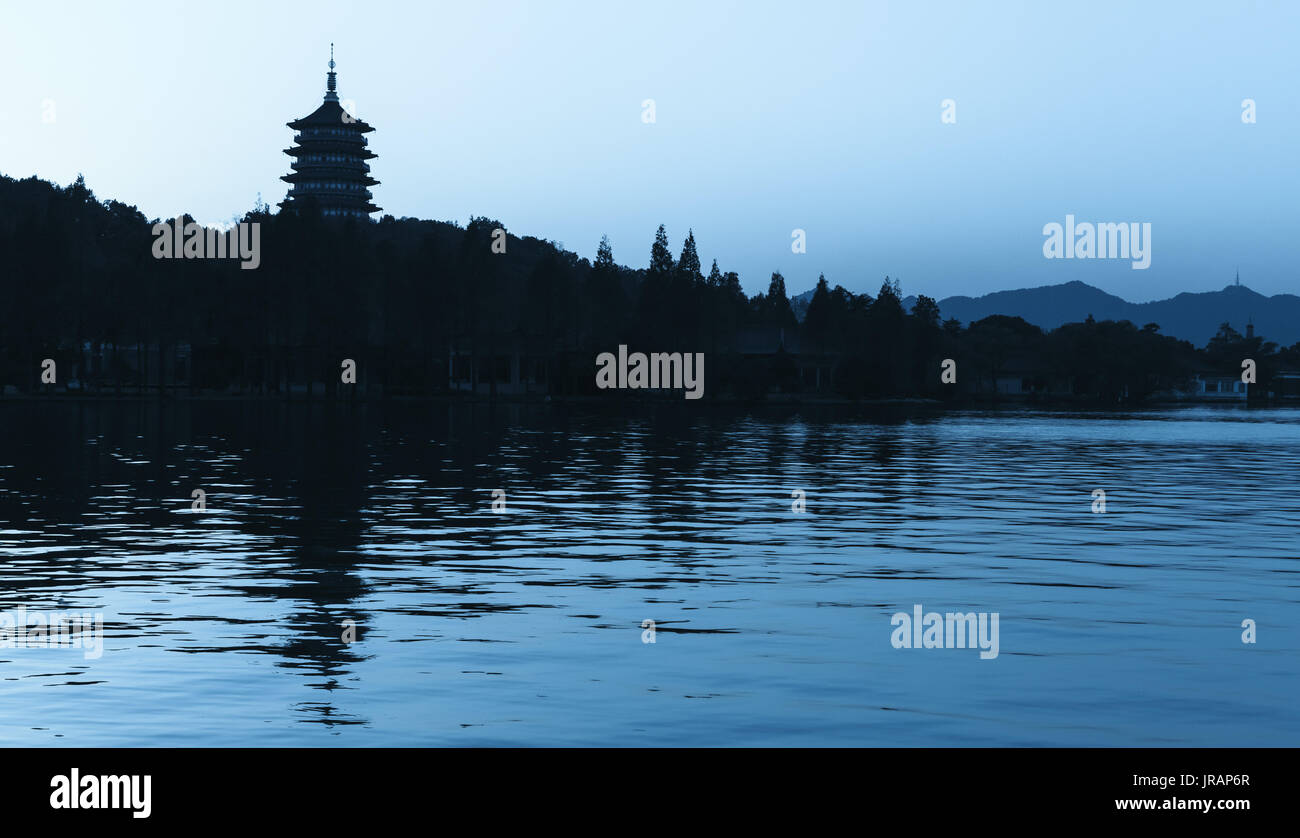 Black silhouette of traditional Chinese pagoda on blue evening sky background. Coast of West Lake. Famous public park of Hangzhou city, China Stock Photo