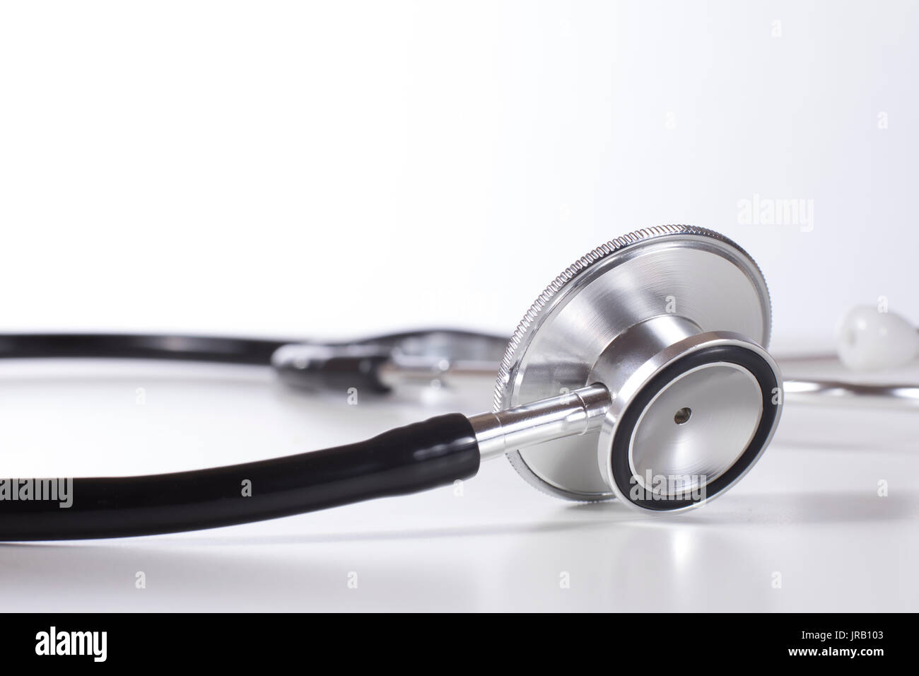 Chestpiece of acoustic stethoscope in close-up against plain background Stock Photo