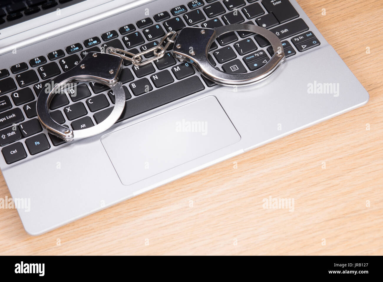 Handcuffs lying on an open laptop computer keyboard in a concept of ...