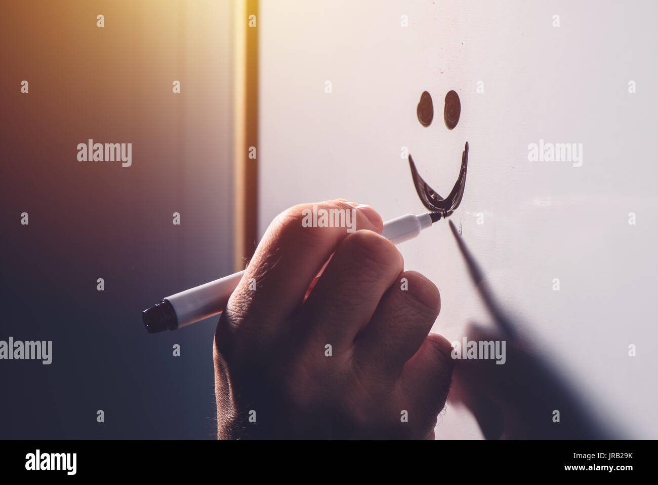 Male hand drawing smiley emoticon on office whiteboard, happy satisfied businessman during business results presentation, selective focus Stock Photo